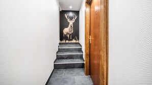 A staircase with a deer mural, a wooden door, and a textured wall. - Apartment "Au Rêve Savoyard 5" with Mountain View for 4 People (Morillon)