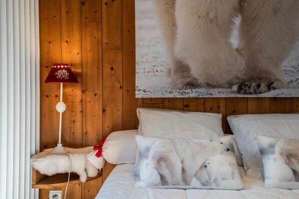 A wooden-paneled room with a bed, pillows, a lamp, and a polar bear image on the wall.