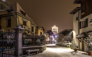 Una strada innevata con edifici, un cancello e una torre in lontananza.