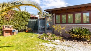 Un bâtiment en briques doté d’un patio couvert, d’une pelouse et de diverses plantes.