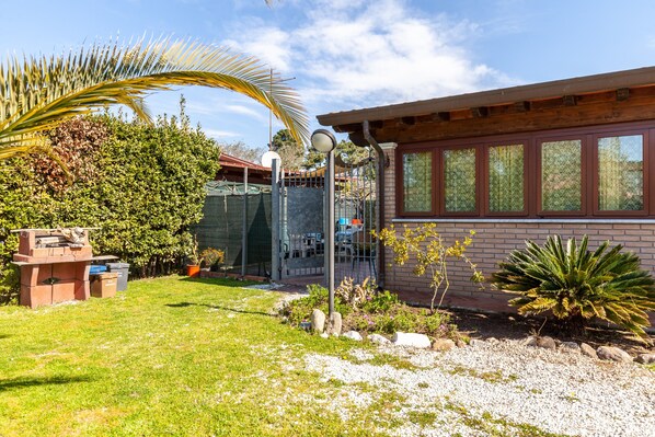 Een bakstenen gebouw met een overdekte patio, een gazon en diverse planten.