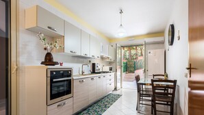 A modern kitchen with white cabinets, stainless steel appliances, and a dining area with a table and chairs. - Holiday Apartment 'Paradiso Marino' with Terrace, Garden and Wi-Fi (Cefalù)