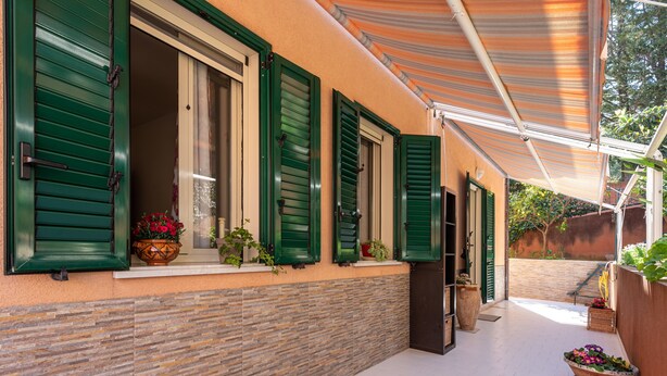 A covered outdoor area with a tiled floor, green shutters on windows, and potted plants. - Holiday Apartment 'Paradiso Marino' with Terrace, Garden and Wi-Fi (Cefalù)