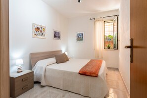 Une chambre à coucher avec un lit, une table de chevet, une lampe et des rideaux.