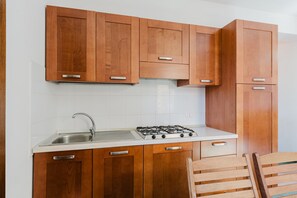 A kitchen with wooden cabinets, a stainless steel sink, and a gas stove.