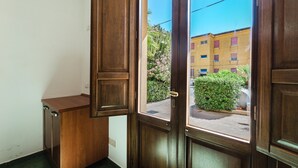A wooden door with a view of a building and a bush.