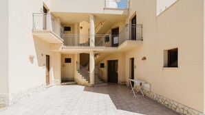 A multi-level residential building with balconies, a staircase, and a tiled courtyard.