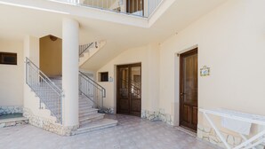 A building with a staircase, a door, and a balcony.
