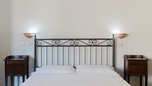 A bed with a metal headboard, two bedside tables, and wall-mounted light fixtures.