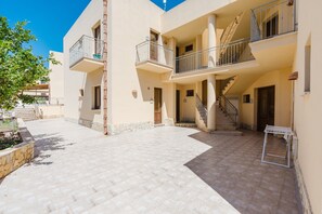 A multi-story building with balconies, a staircase, and a paved courtyard.