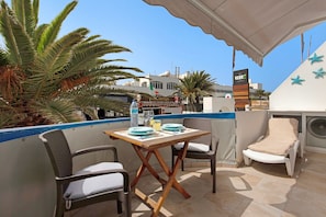 Une terrasse extérieure avec une table, des chaises et un fauteuil de relaxation.