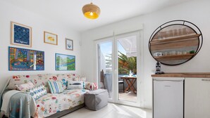 Ein Zimmer mit einer Sitzecke, einem Esstisch, einer Küchenzeile und einer Glasschiebetür, die auf eine Terrasse im Freien führt.