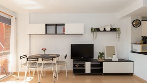 Un salon moderne avec un téléviseur, des sièges, une petite table et une plante.
