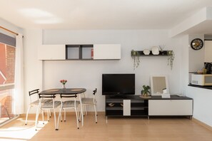 A modern living room with a TV, seating, a small table, and a plant.