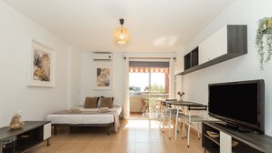 Une chambre d’hôtel moderne équipée d’un lit, d’une télévision, d’un balcon et d’un coin repas.