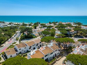 A coastal town with white buildings, trees, and a clear blue sea.