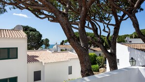Un bâtiment blanc avec un toit recouvert de tuiles, un grand arbre et un ciel bleu dégagé.