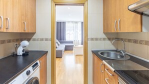 A modern kitchen with wooden cabinets, a built-in washing machine, a coffee maker, and a sink.