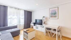 A modern living room with a sofa, a TV, a desk, and a chair.