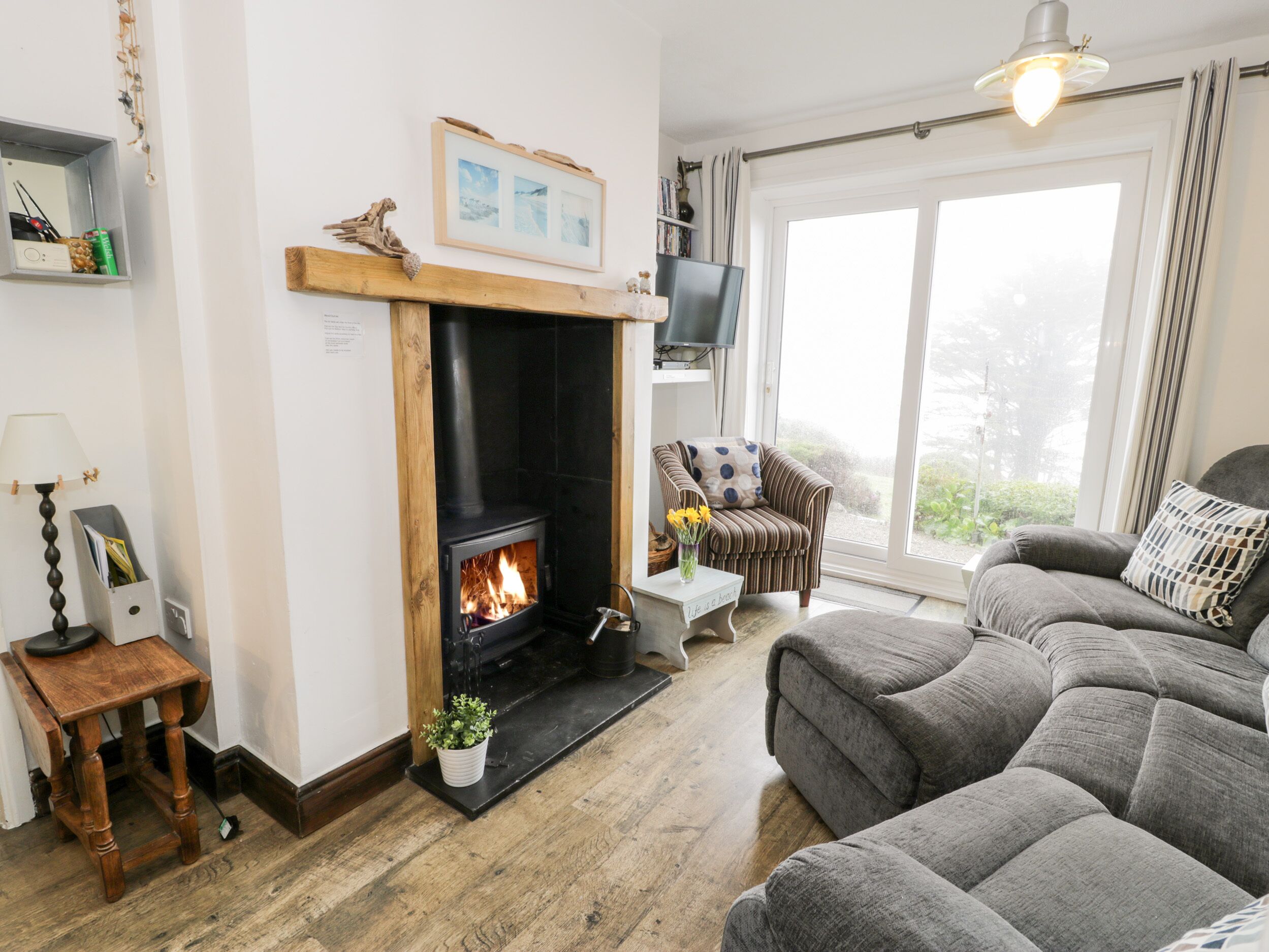 A cozy living room with a fireplace, comfortable seating, and a large window.
