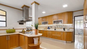 Eine moderne Küche mit Holzschränken, einer Edelstahl-Dunstabzugshaube, einer eingebauten Mikrowelle und einem Blumentopf.