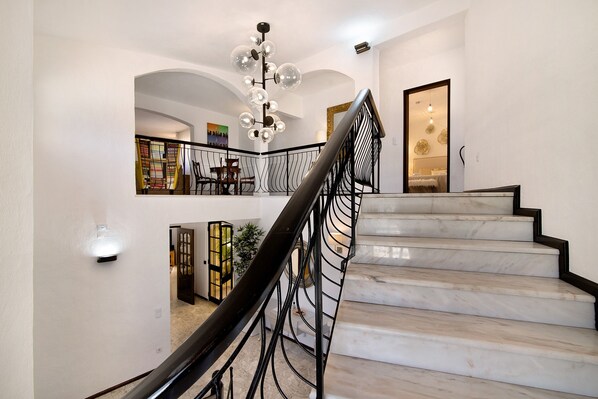 Un escalier en marbre, agrémenté d’une rampe en métal noir, mène à un palier situé au deuxième étage.