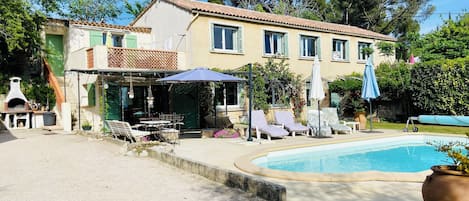 Une maison à deux étages avec une piscine, un espace extérieur aménagé et un coin barbecue.