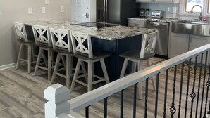A modern kitchen with a central island, stainless steel appliances, and a dining area with white chairs. - Lakefront,  Great, wide-water views. Near bridge
 (Moneta)