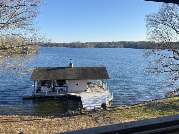 Une péniche dotée d’une terrasse couverte et d’une petite cabine, amarrée sur un lac paisible.