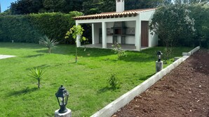 A modern house with a patio, surrounded by a well-maintained lawn and trees. - Historic Stable House | Private Patio & Farm Views (Lagoa, São Miguel Açores)