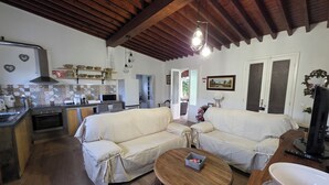 A cozy living area with a sofa, a coffee table, and a television. - Historic Stable House | Private Patio & Farm Views (Lagoa, São Miguel Açores)