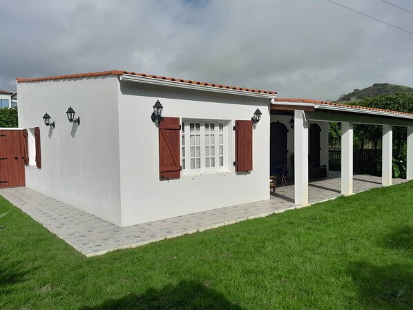 A white building with a red-tiled roof, a covered patio area, and a small window with shutters. - Historic Azorean Stable House | Private Patio & Farm Views (Lagoa, São Miguel Açores)