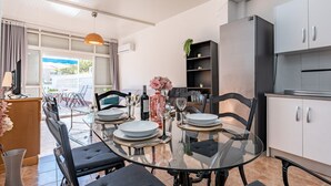 Eine moderne Küche mit Essbereich, ausgestattet mit einem Glastisch, schwarzen Stühlen und einem eingebauten Backofen.