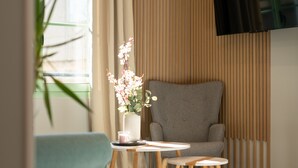 A modern living room with a grey armchair, a small white table with a vase of flowers, and a blue chair. - Modern Apartment - Promenade des Anglais in Nice (Nice)