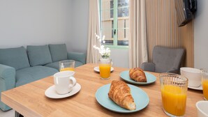 A breakfast setup with a wooden table, two plates with croissants, a white cup, and two glasses of orange juice. - Modern Apartment - Promenade des Anglais in Nice (Nice)