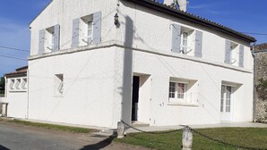 Kaksikerroksinen valkoinen rakennus, jossa on tiilikatto, pääovi ja pieni etupiha.