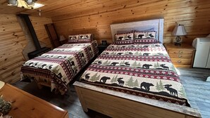 Eine Hütte mit zwei Betten, einem Deckenventilator, einem Holzofen und einem Dachfenster.