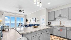 Una cocina moderna con armarios grises, una isla central y vistas al exterior.