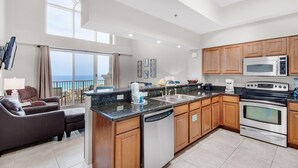 A modern kitchen with granite countertops, wooden cabinets, a dishwasher, a stove, and a microwave.