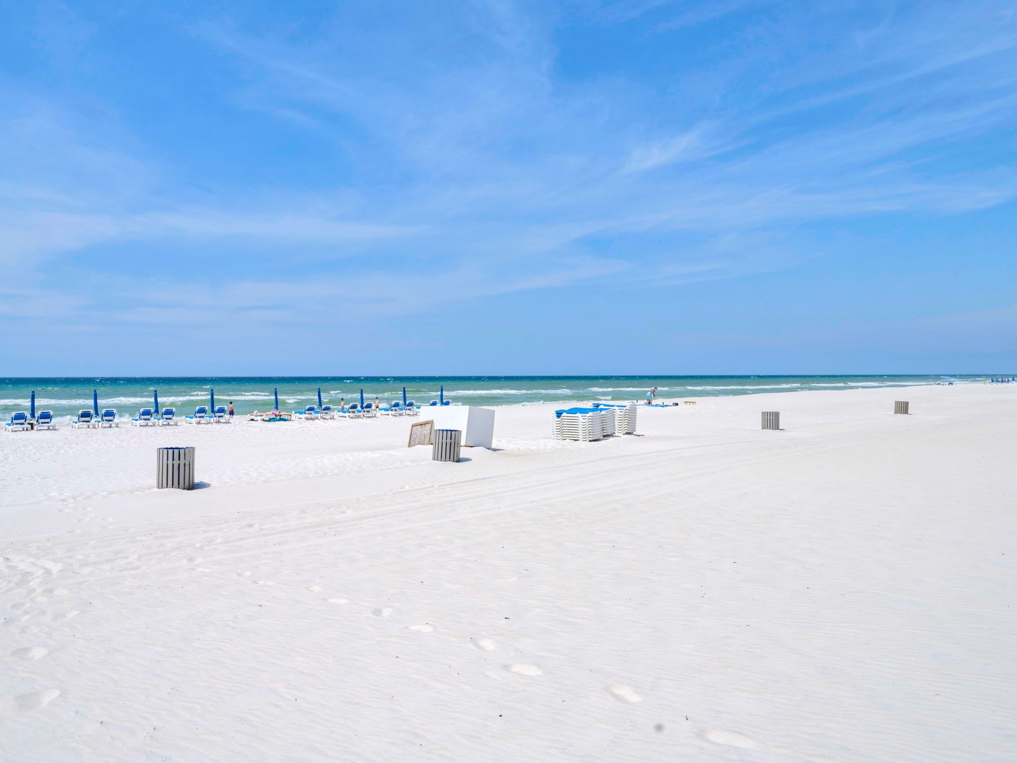 A beach with white sand, clear blue sky, and calm sea.