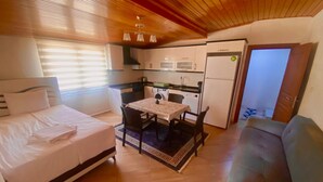 Una habitación compacta con cama, una mesa de comedor con sillas, una kitchenette y un sofá.