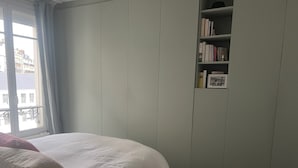 Una camera da letto con un letto, un armadio, una libreria e una finestra con tende.