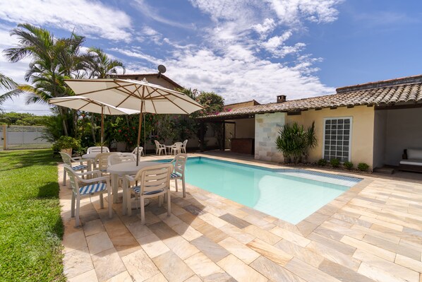 A pool area with a tiled deck, outdoor furniture, and a covered seating area. - Pousada Maré (Búzios)