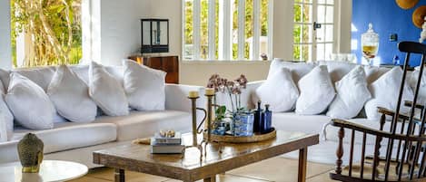 A living room with a white sofa, a wooden coffee table, and a wooden chair.