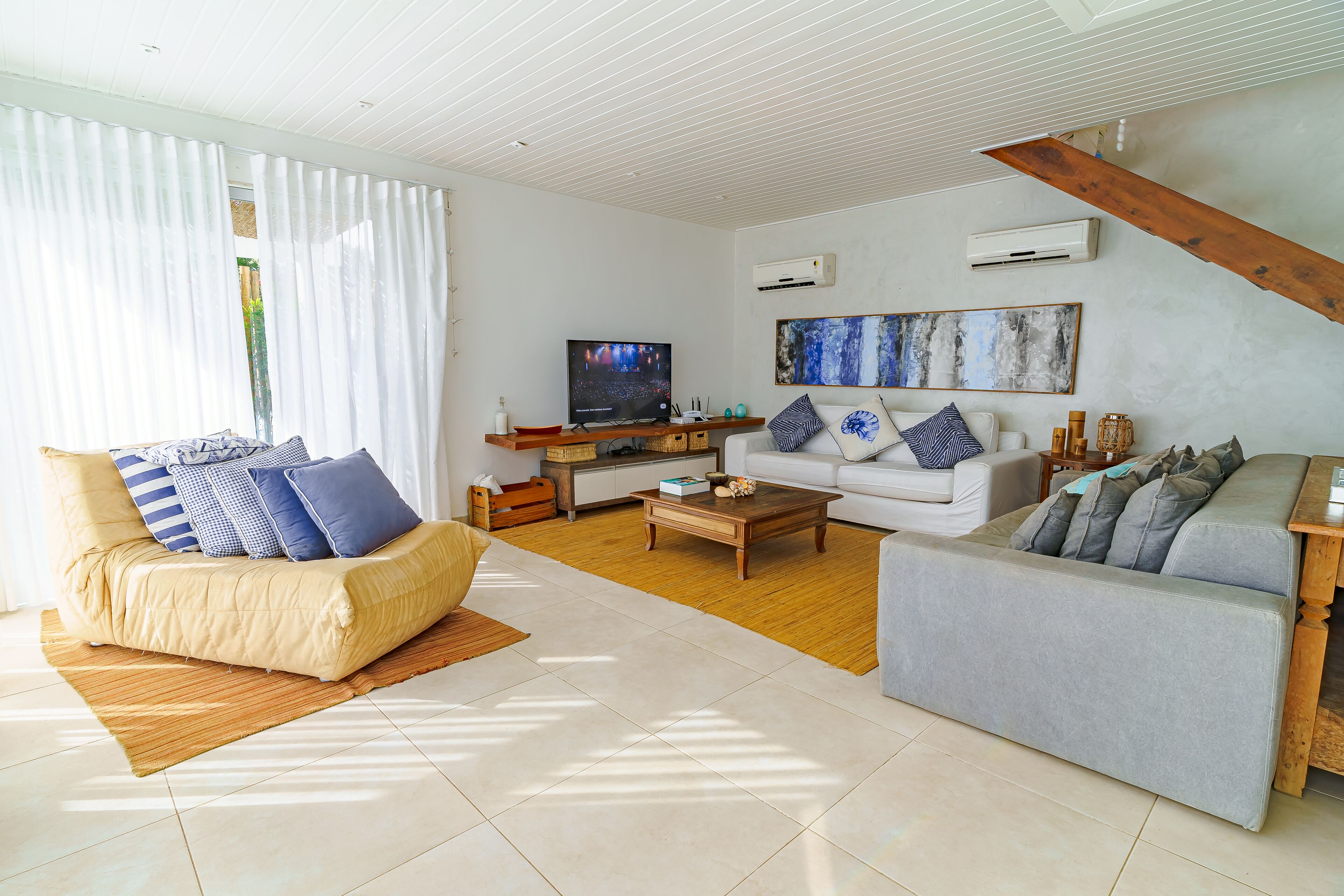 Una sala de estar moderna con un sofá color beige, un sofá gris, una mesa de centro de madera y un televisor.