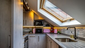 Een compacte keuken met dakraam, moderne apparatuur en een betegelde muur.