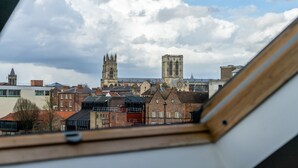 Uitzicht vanuit een raam op een stadsgezicht met historische gebouwen en een opvallende kerktoren.