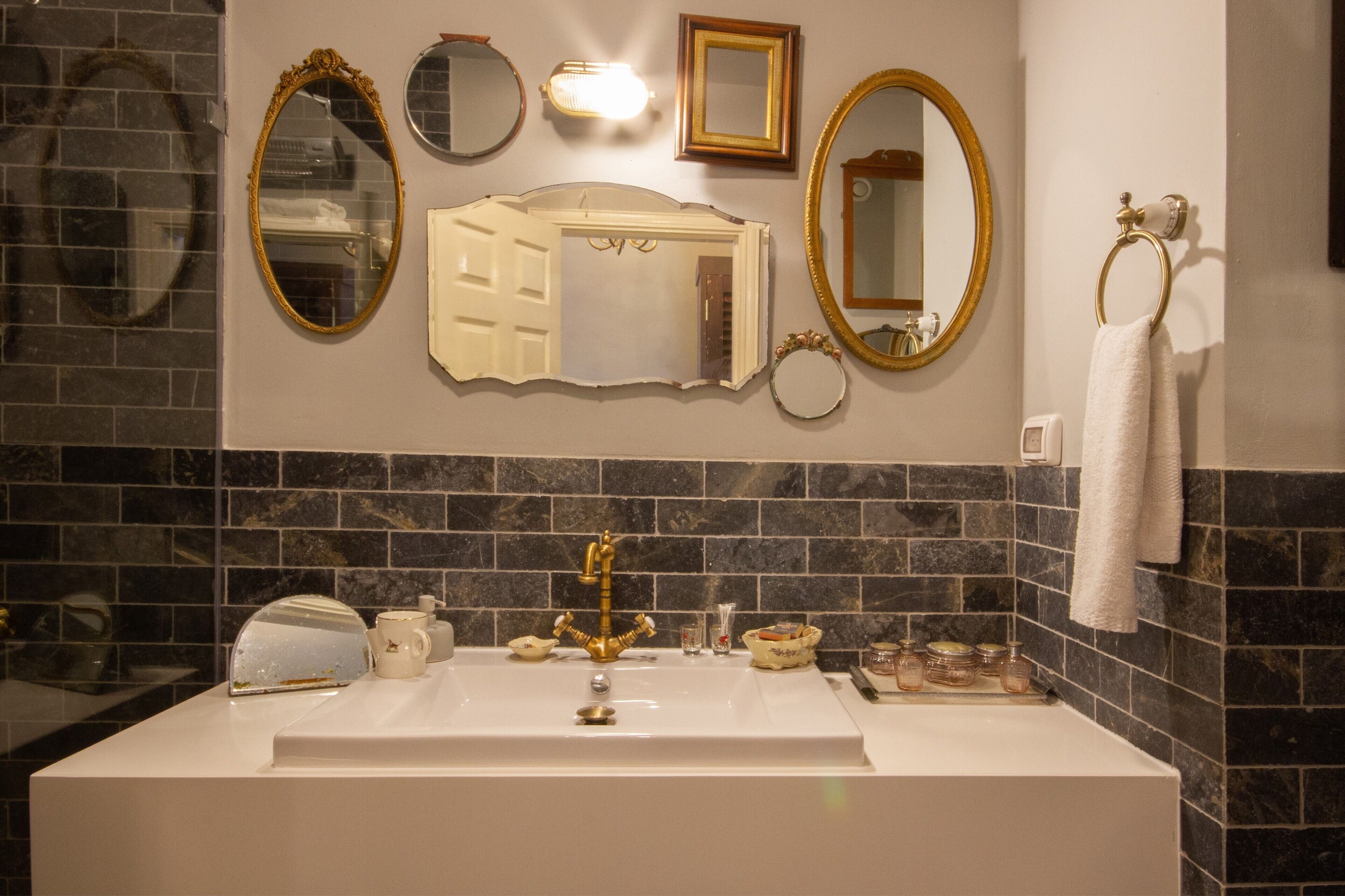A bathroom with a large white sink, multiple mirrors, and a towel ring.
