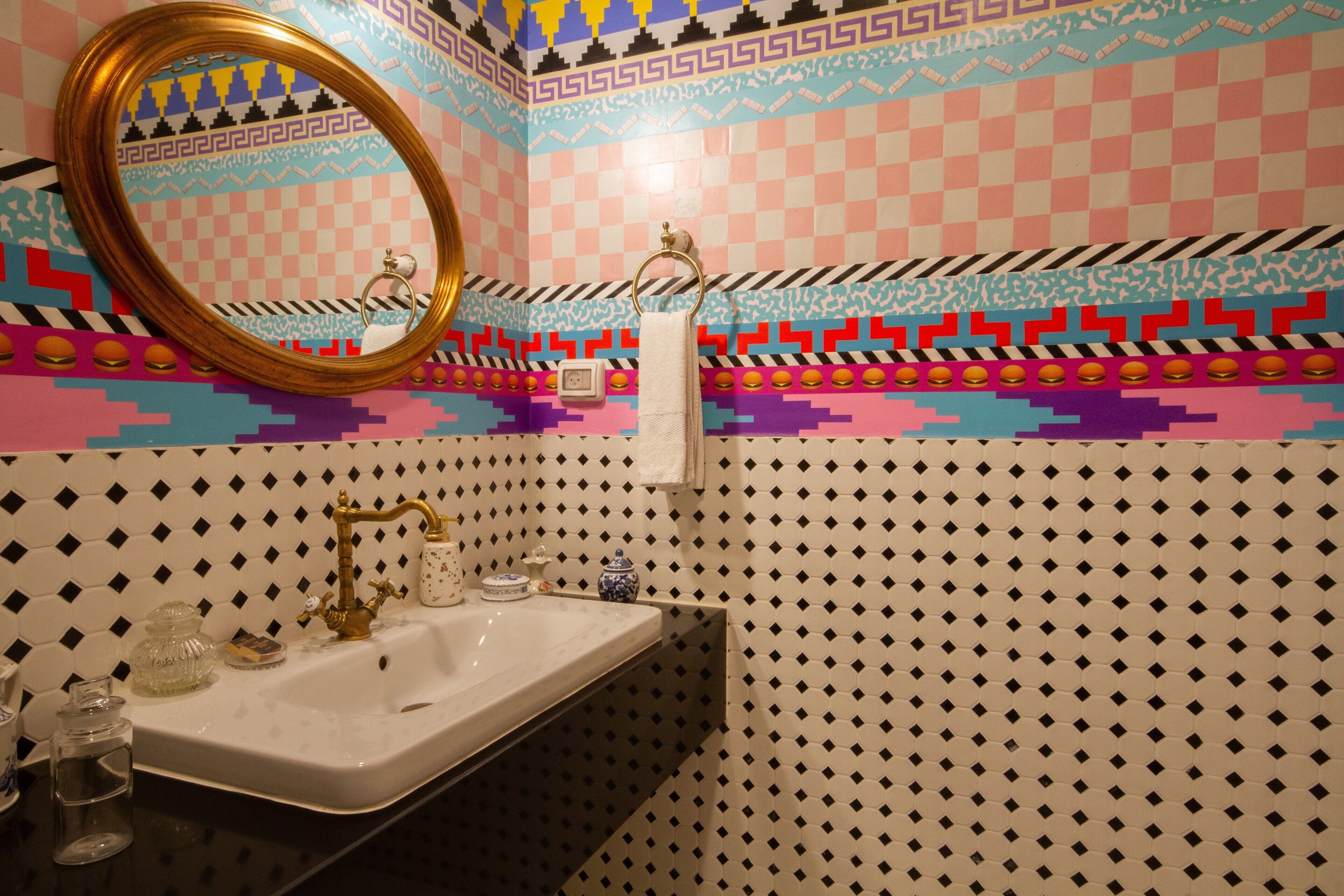 A bathroom with a sink, mirror, and patterned tiles.