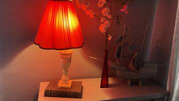 Une table avec une lampe rouge, un livre intitulé « L’évolution moderne de la photographie » et un vase rempli de fleurs.